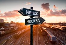 Указатели «Минск» и «Москва» на фоне путей грузовой станции с составами на закате